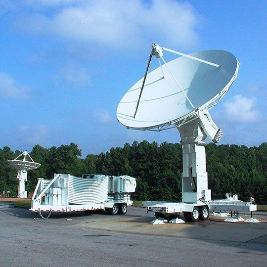 Large, white transportable antenna parked on pavement