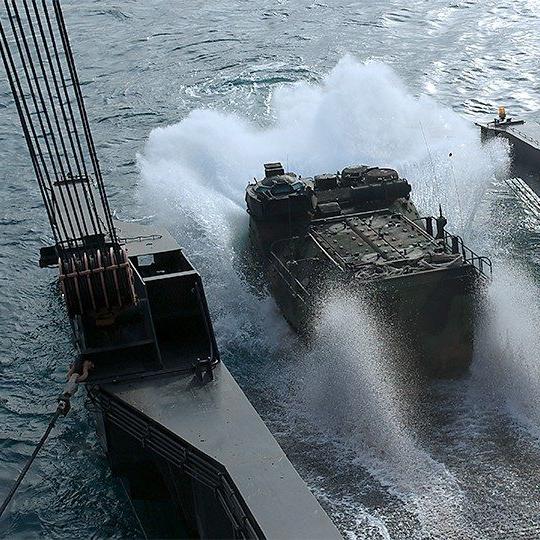 Military vehicle driving into the water off of a ship