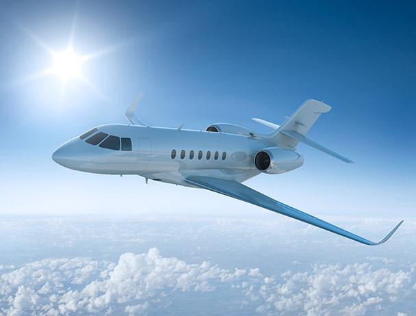 Private business jet flying above 的 clouds against a sunlit sky