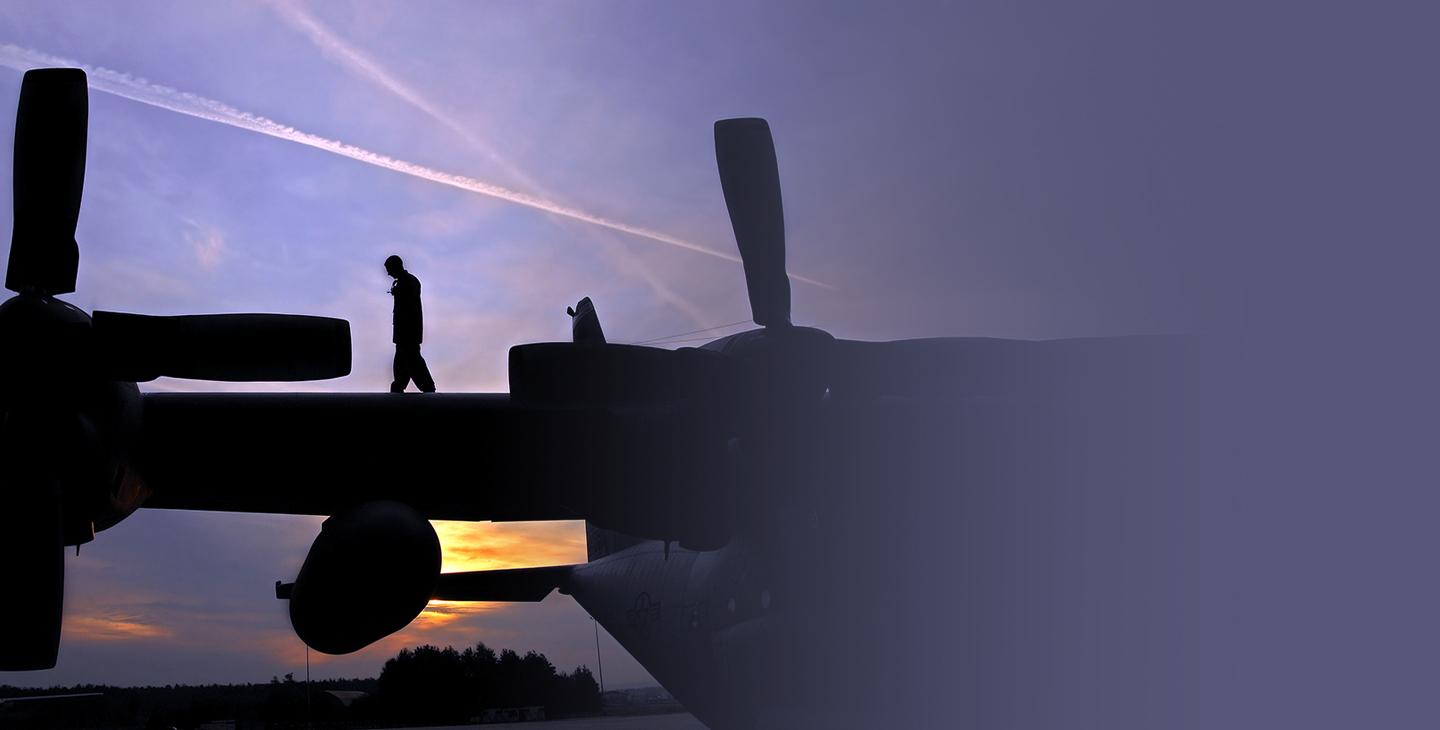 Soldier on the wing of a military aircarft at sunset
