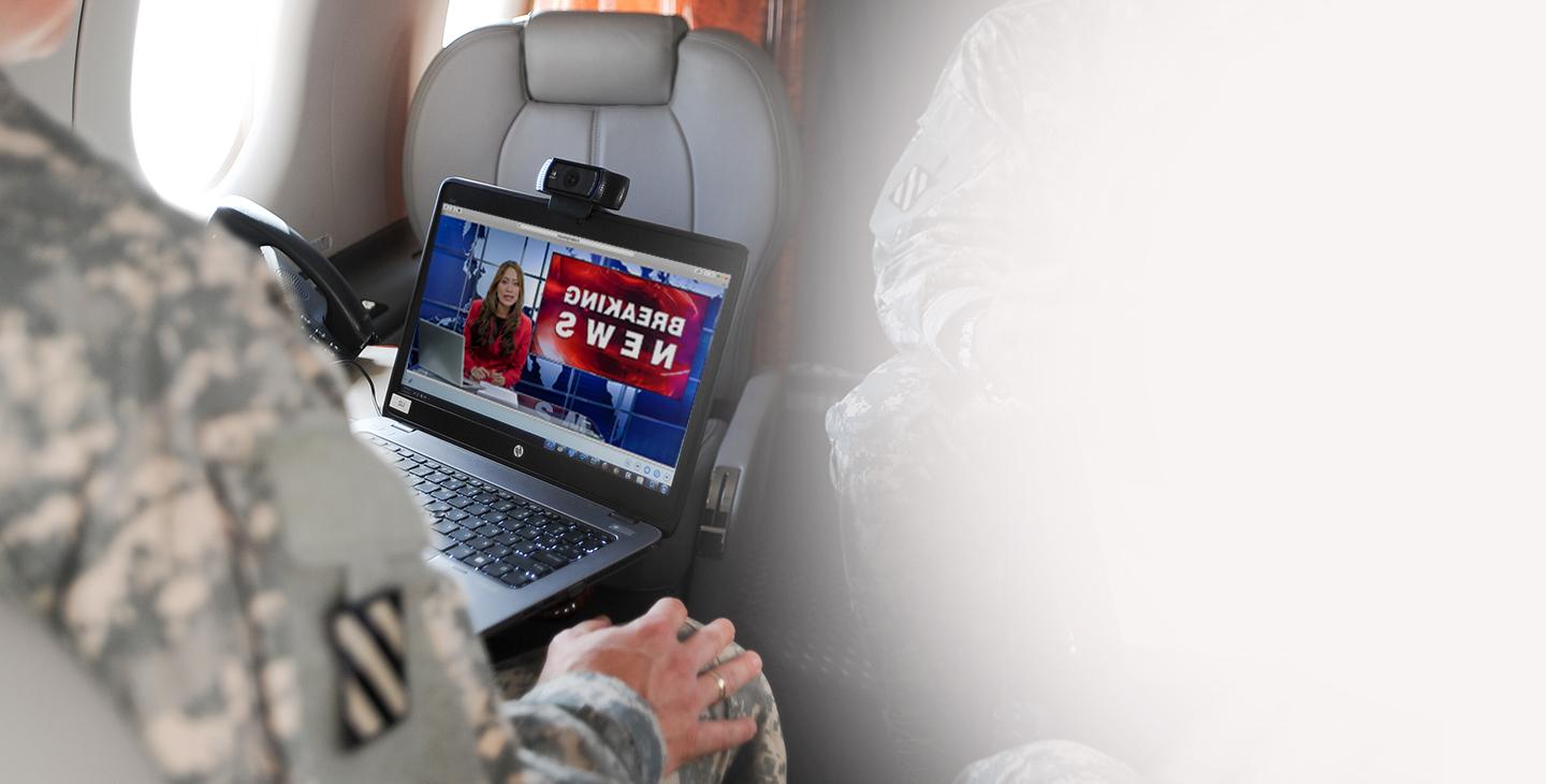 Senior leader on government aircraft equipped with aircraft technology, watching the news on laptop