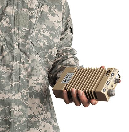 一个穿着军装的人拿着一个棕色的IPS-250X以太网加密器的特写