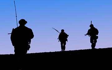 Silhouettes of 3 solders againt the night sky