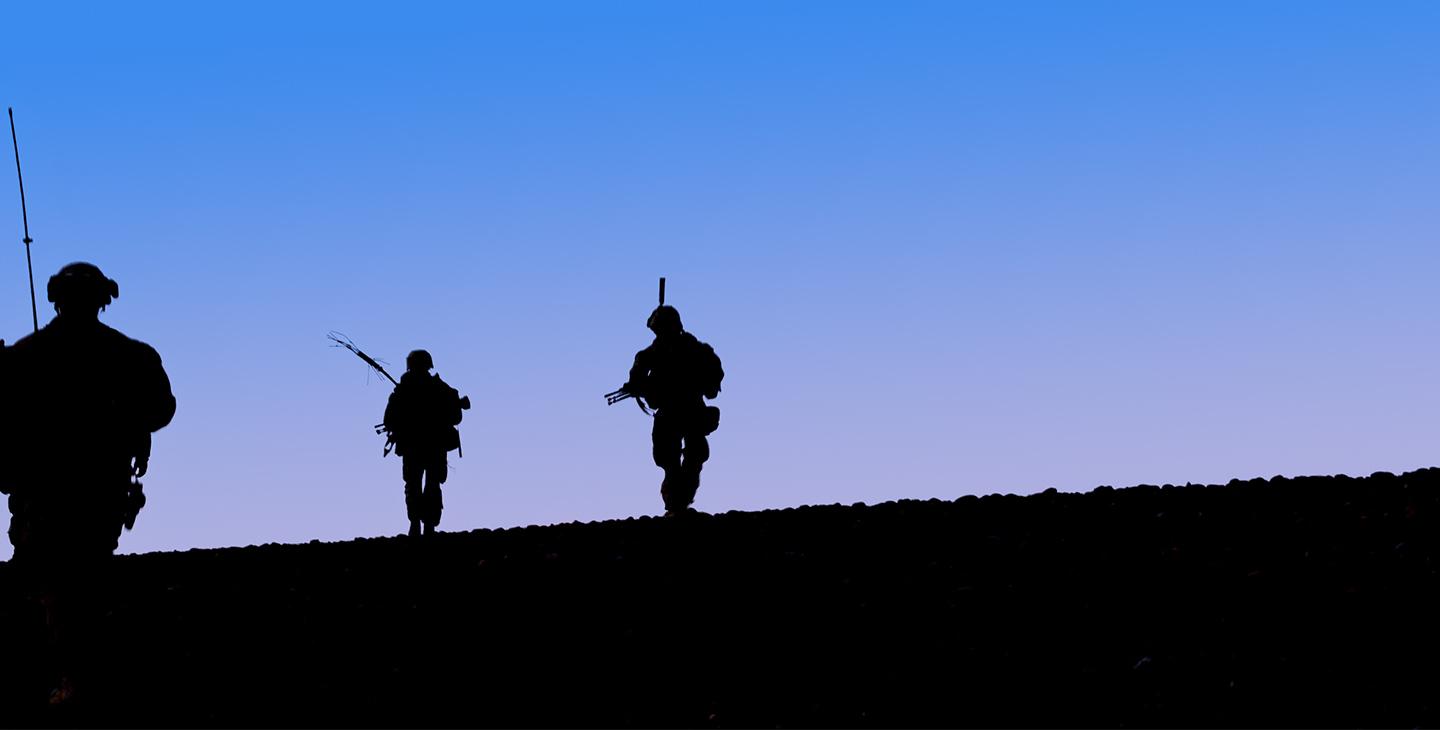Silhouettes of three soldiers at dusk