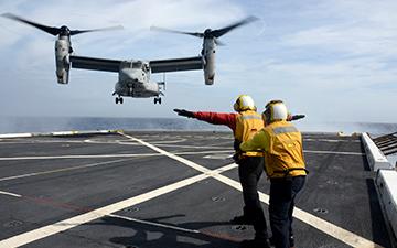 Two people watching a MV-22 take off  from an aircraft 航空公司