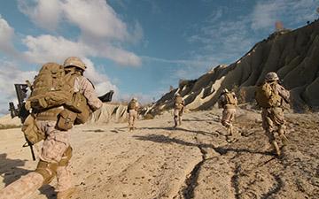 Warfighters running up a dirt hill