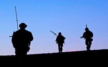 黄昏时分，三名士兵在战场上的剪影映衬着逐渐暗淡的蓝天