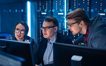 两男一女，都戴着眼镜，在服务器机房的电脑上使用Viasat软件